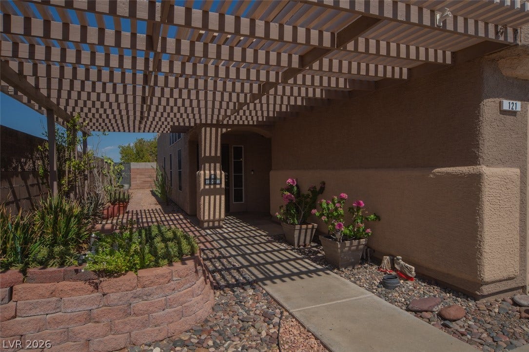 121 Heather Drive, Henderson, NV 89002 A shaded concrete walkway leads to the private entrance under a large wooden pergola.