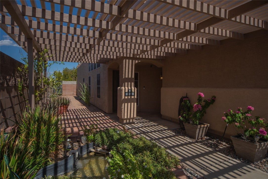 121 Heather Drive, Henderson, NV 89002 An extensive overhead pergola filters sunlight across the concrete pathway and adjacent garden water feature.