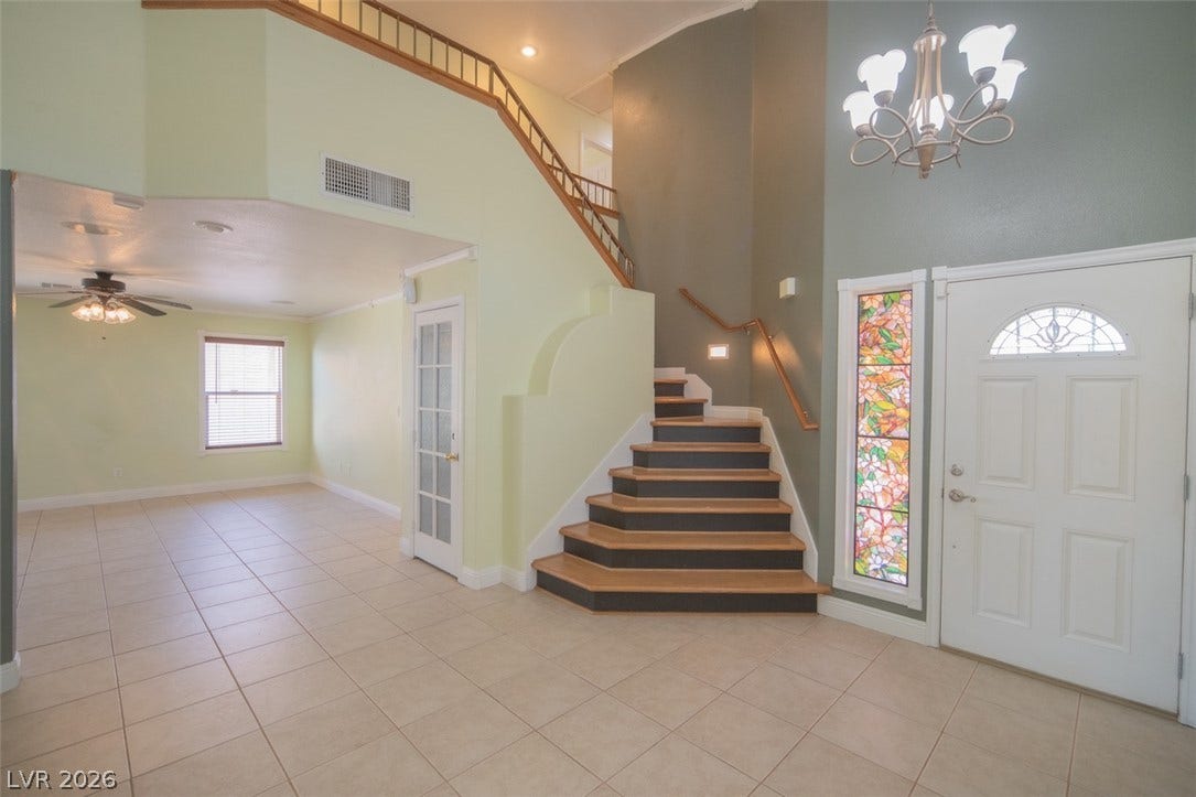 121 Heather Drive, Henderson, NV 89002 Tiled floors and soaring ceilings frame a welcoming entryway featuring a wooden staircase.