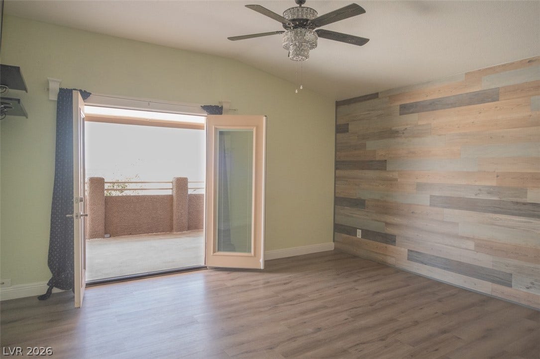 121 Heather Drive, Henderson, NV 89002 Double doors open directly onto a spacious outdoor balcony from this bedroom featuring wood-look floors.