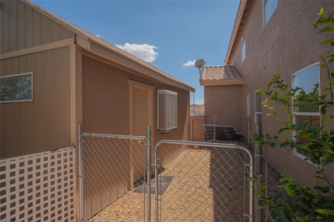 121 Heather Drive, Henderson, NV 89002 Functional side yard space features a secure chain-link gate and a detached storage shed.