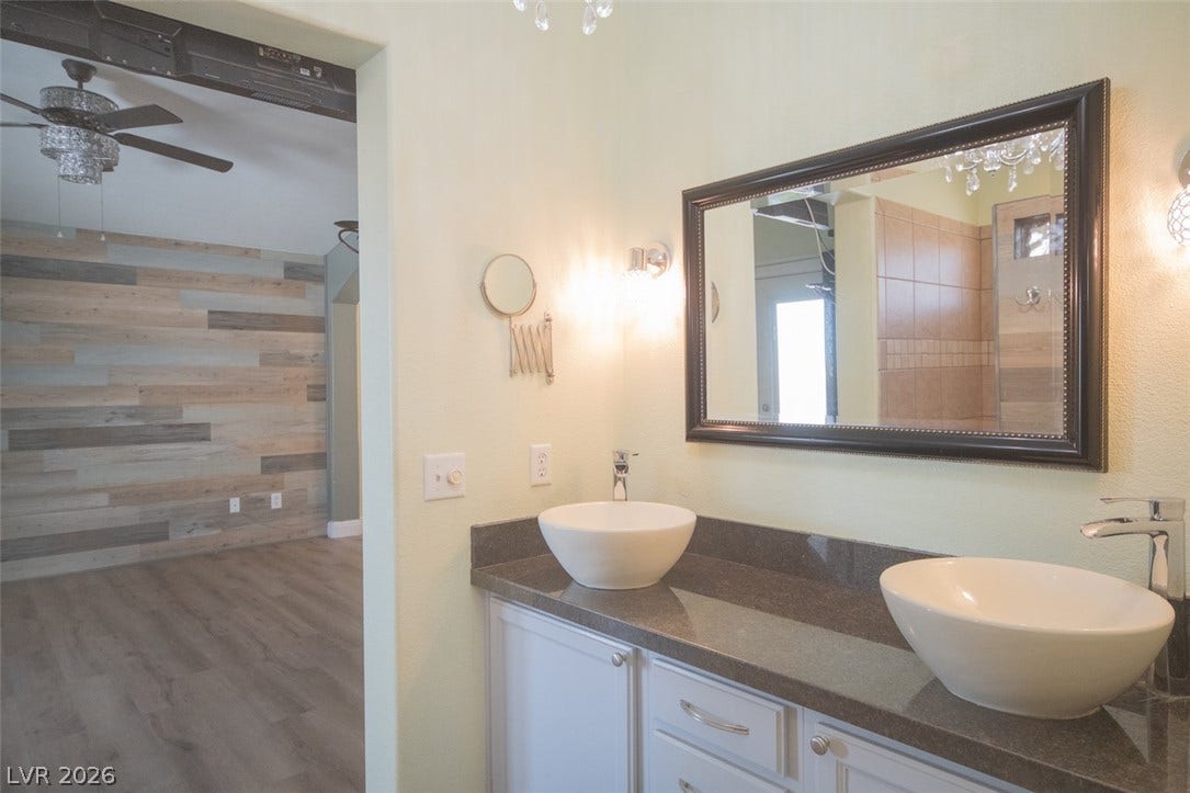 121 Heather Drive, Henderson, NV 89002 Dual vessel sinks sit atop stone counters in a modern bathroom with wood flooring.