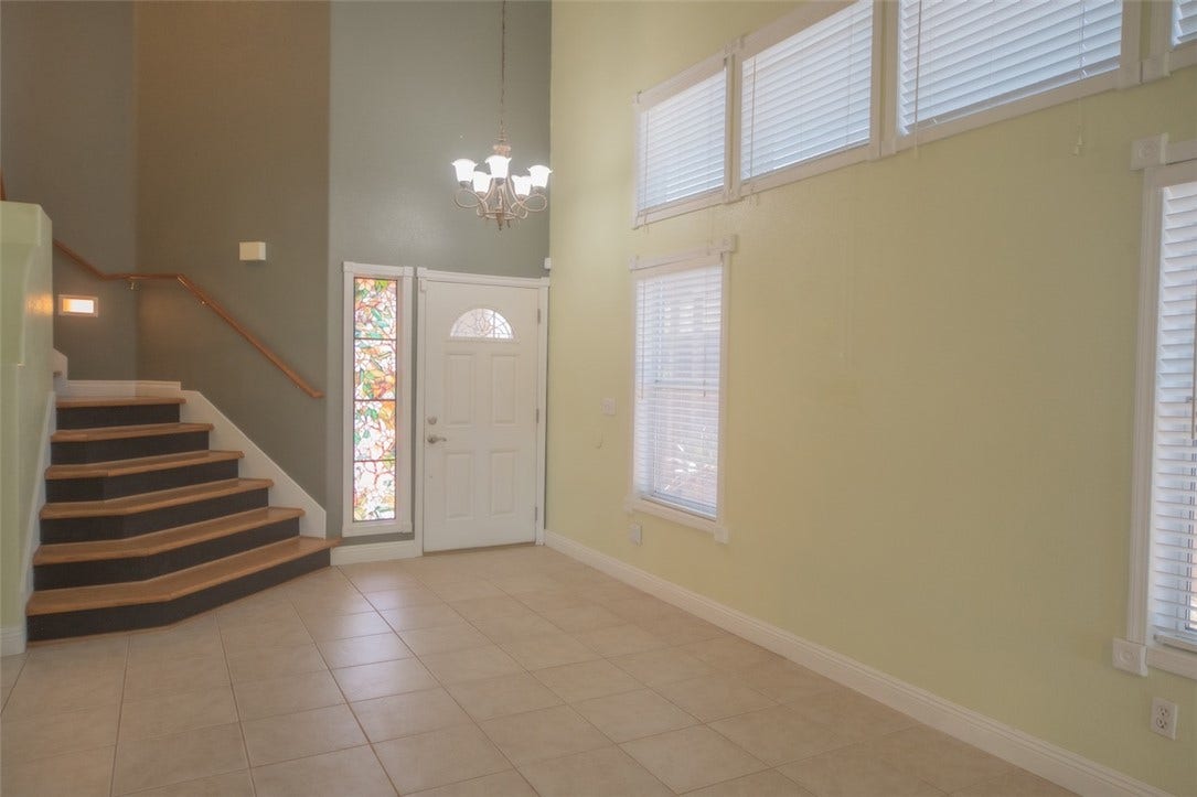 121 Heather Drive, Henderson, NV 89002 High ceilings and tall windows frame this light-filled entryway featuring tiled floors and carpeted stairs.