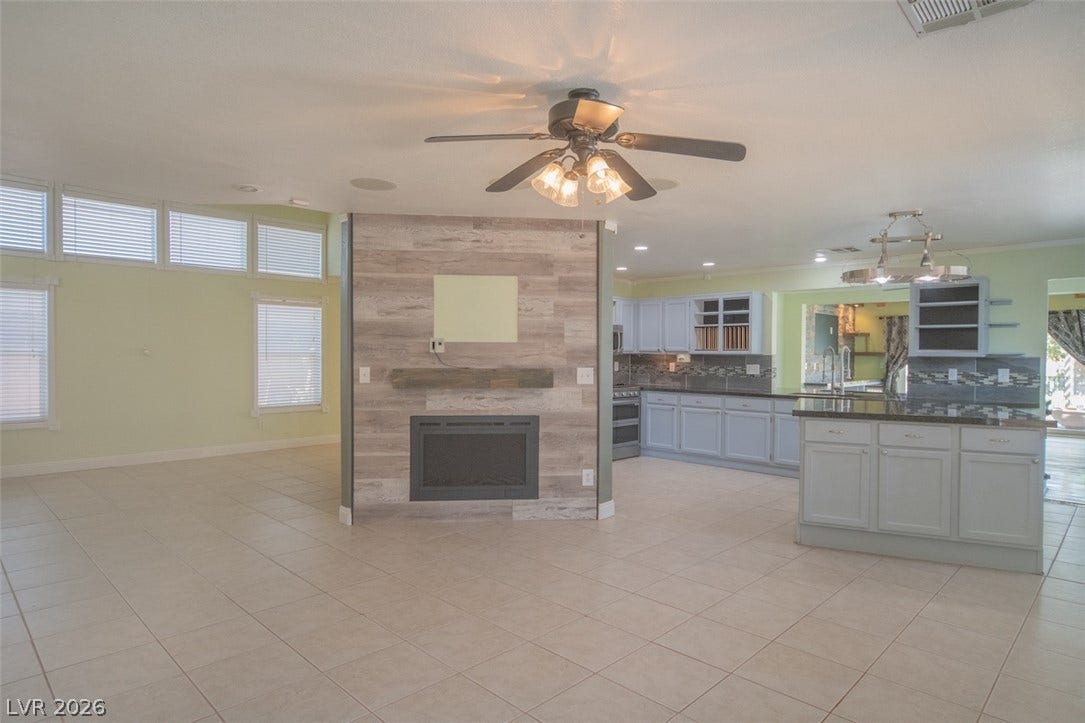 121 Heather Drive, Henderson, NV 89002 Tiled flooring flows through an open-concept living area centered around a modern wood-paneled fireplace.