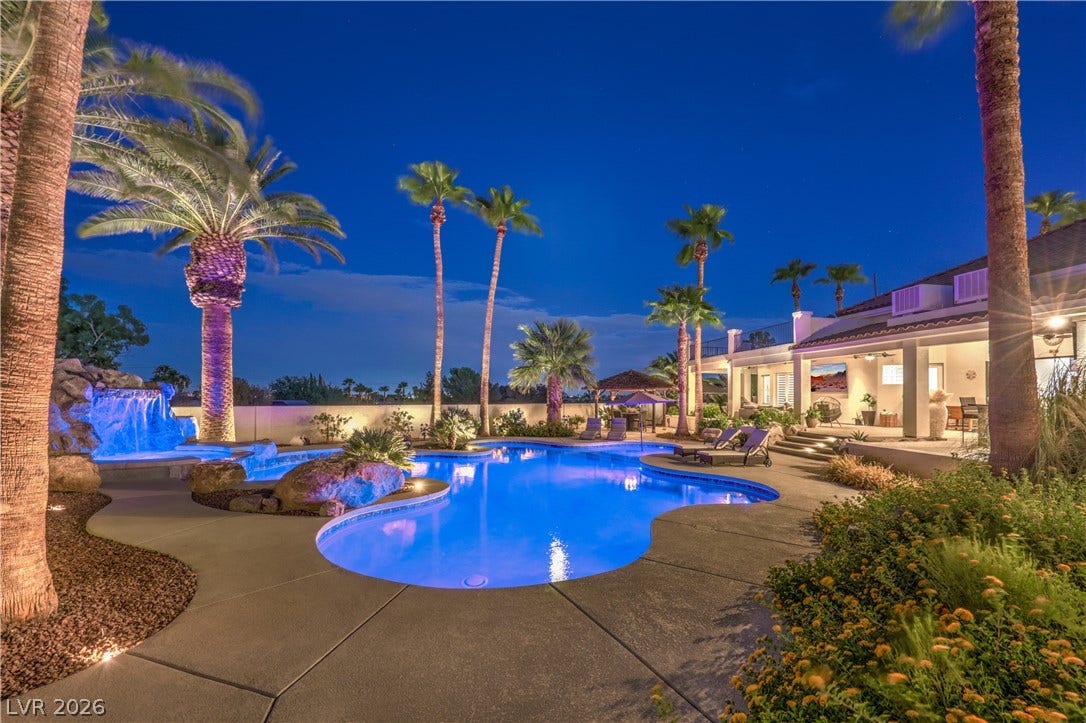 Lush tropical landscaping and a cascading rock waterfall frame this resort-style swimming pool.