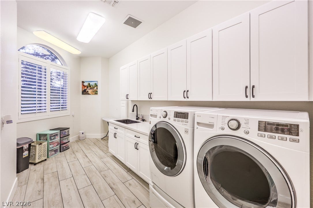 A spacious utility room offers abundant cabinetry and tile flooring beneath arched window details.