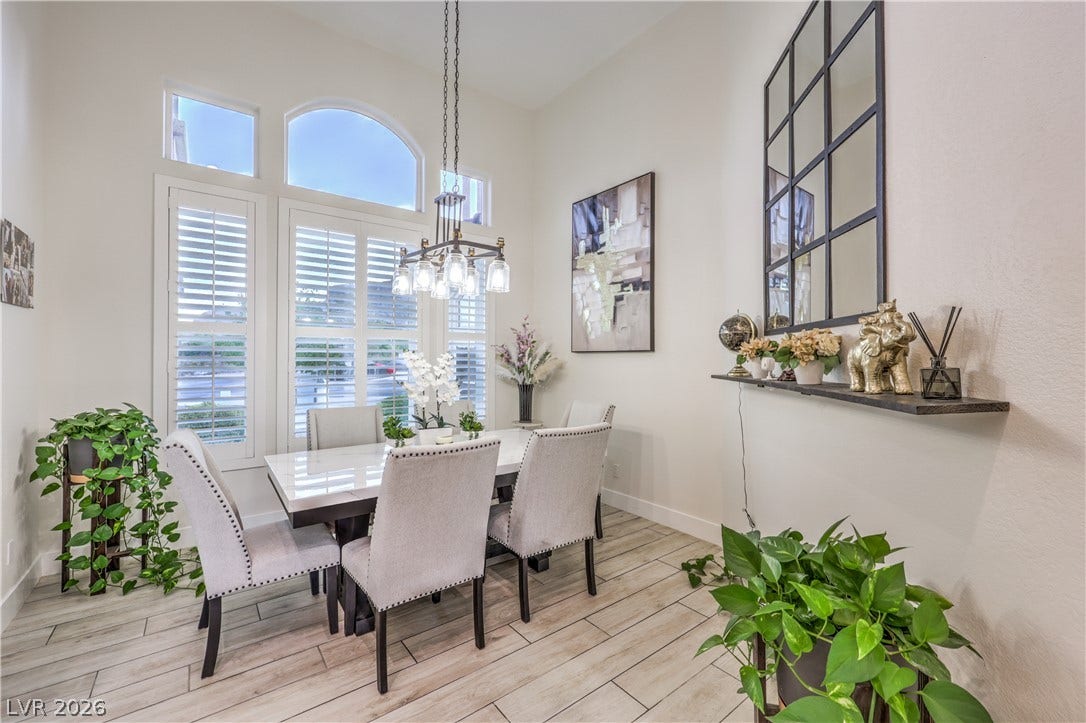 High ceilings and arched windows with plantation shutters frame this airy dining space.