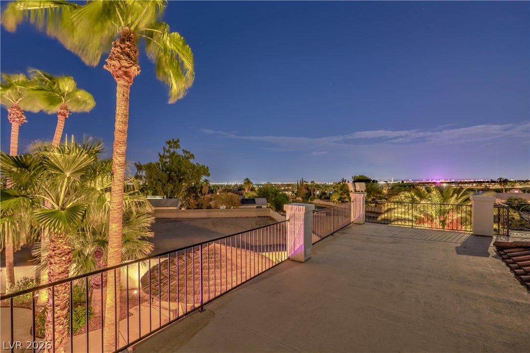 An expansive upper-level terrace looks out over distant city lights under the desert night sky.