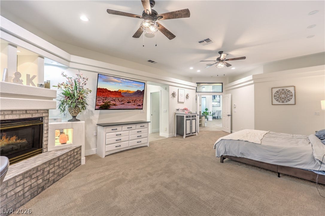 An inviting stone fireplace highlights this comfortable bedroom with soft carpeting and high ceilings.
