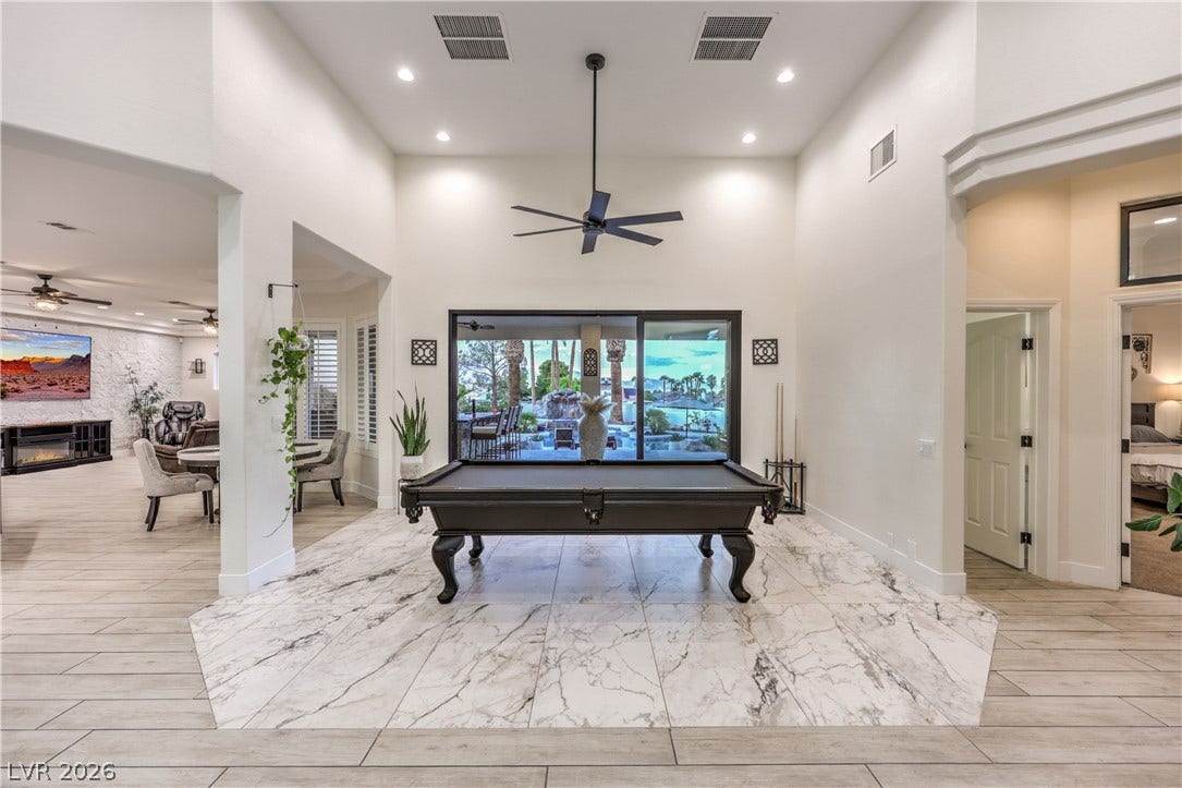 Gleaming tile floors and soaring ceilings define this light-filled game area bordering the patio.
