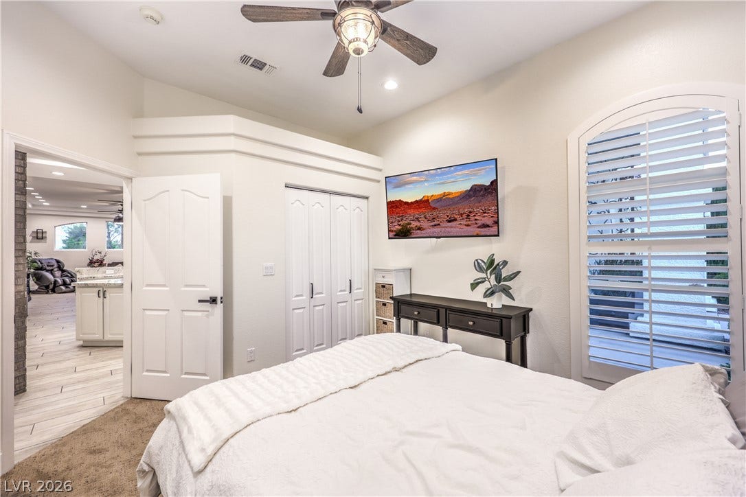Plentiful natural light fills this cozy bedroom featuring soft carpeting and a vaulted ceiling.