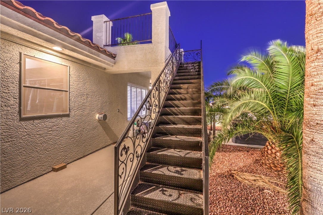An outdoor staircase leads to an upper-level balcony showcasing Spanish tile roof details.