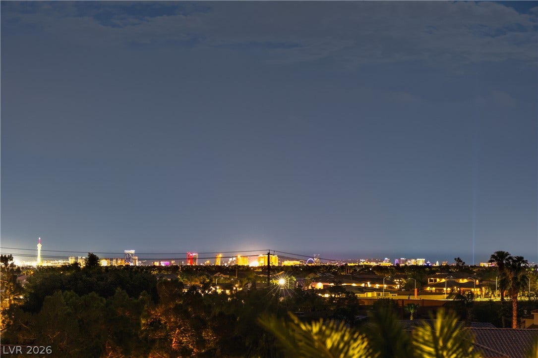 Glittering city lights sparkle across the horizon under an expansive desert evening sky.