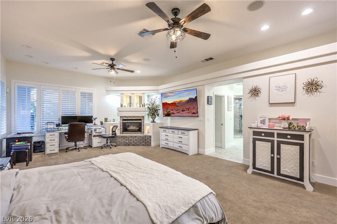 Plush carpeting and a cozy fireplace define this comfortable primary bedroom suite.