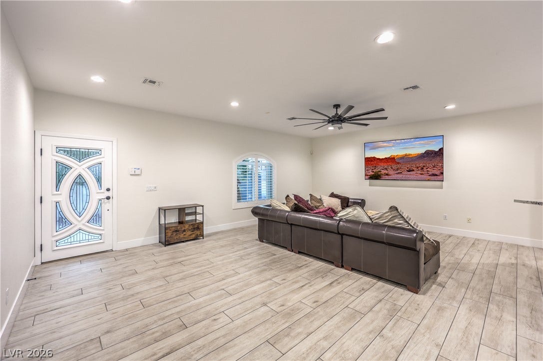 Gleaming wood-look tile floors stretch across a light-filled living space with an ornate entry door.