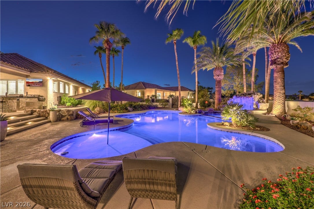 Palm trees and a custom pool with a waterfall create an inviting outdoor oasis.