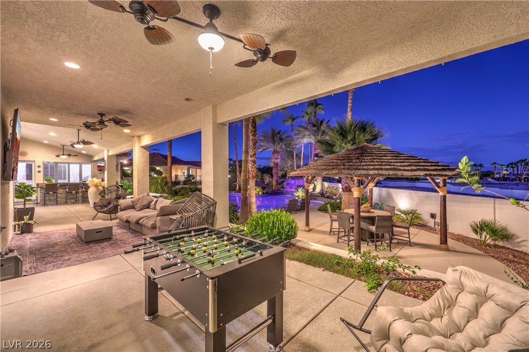 A sheltered concrete terrace looks out onto a poolside oasis framed by palm trees.
