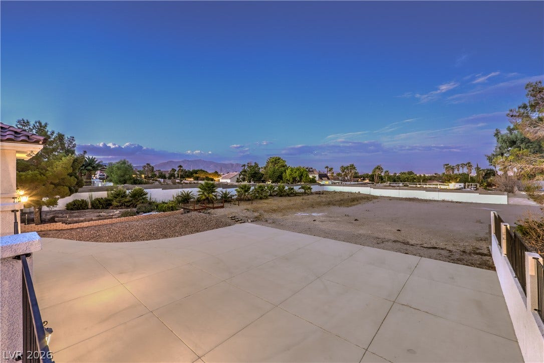 An expansive concrete patio overlooks a spacious yard with distant mountain views.
