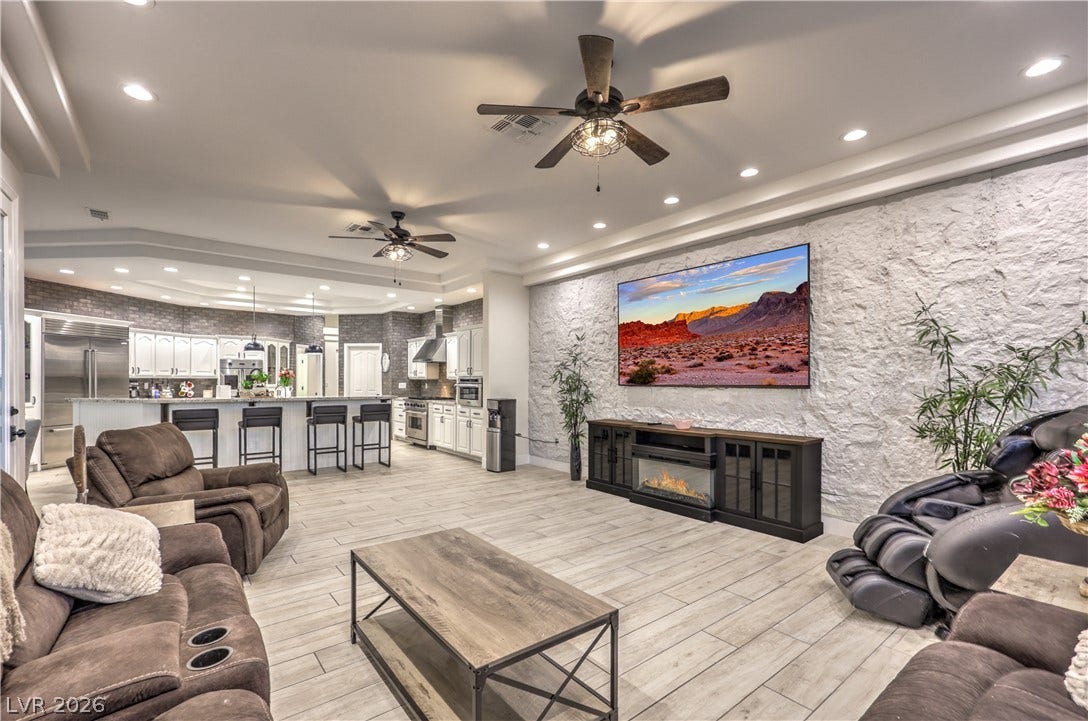 An open floorplan seamlessly connects the stone-textured living area with the modern kitchen beyond.