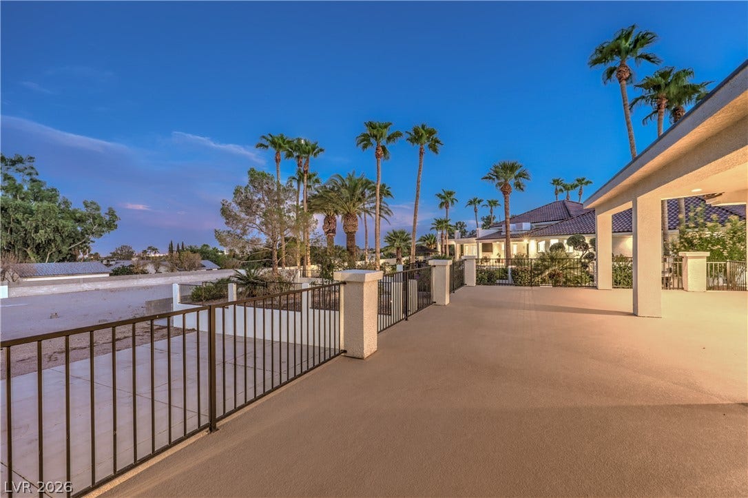 A spacious elevated terrace with secure railings overlooks manicured landscaping and mature palm trees.