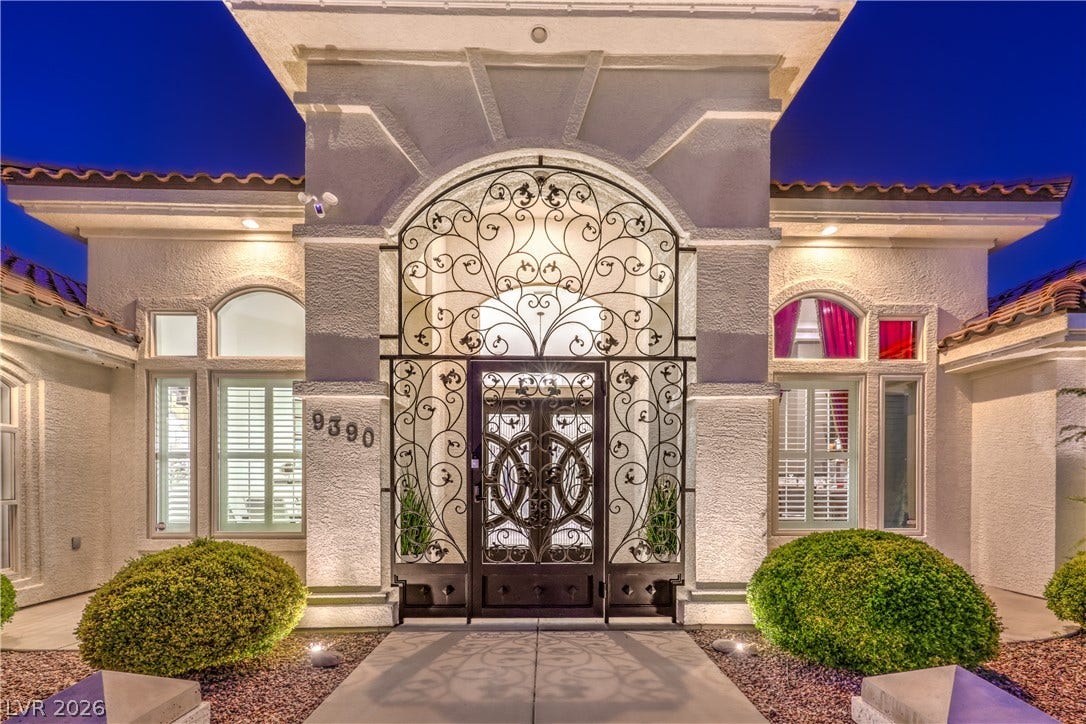 An elegant arched entry with intricate ironwork and integrated lighting creates a memorable first impression.