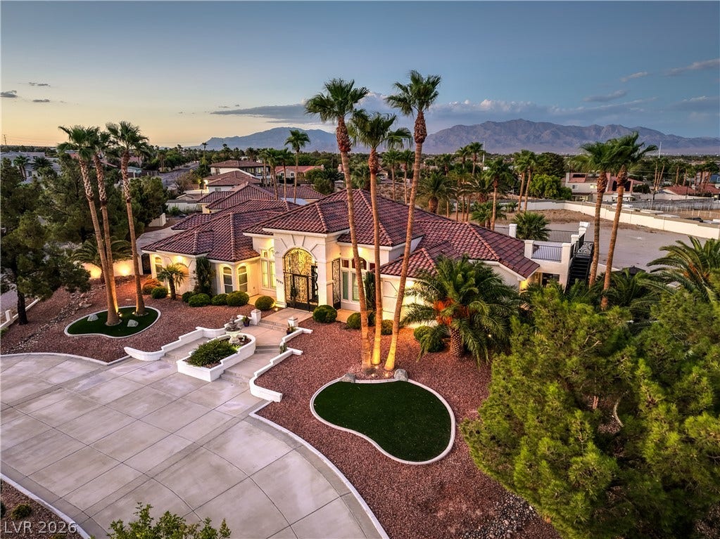 Palm trees frame the elegant exterior of this gated estate with mountain views.