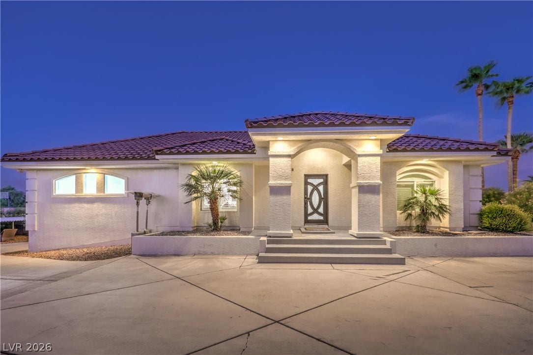 An inviting tiled entry porch highlights the facade of this stucco home at twilight.