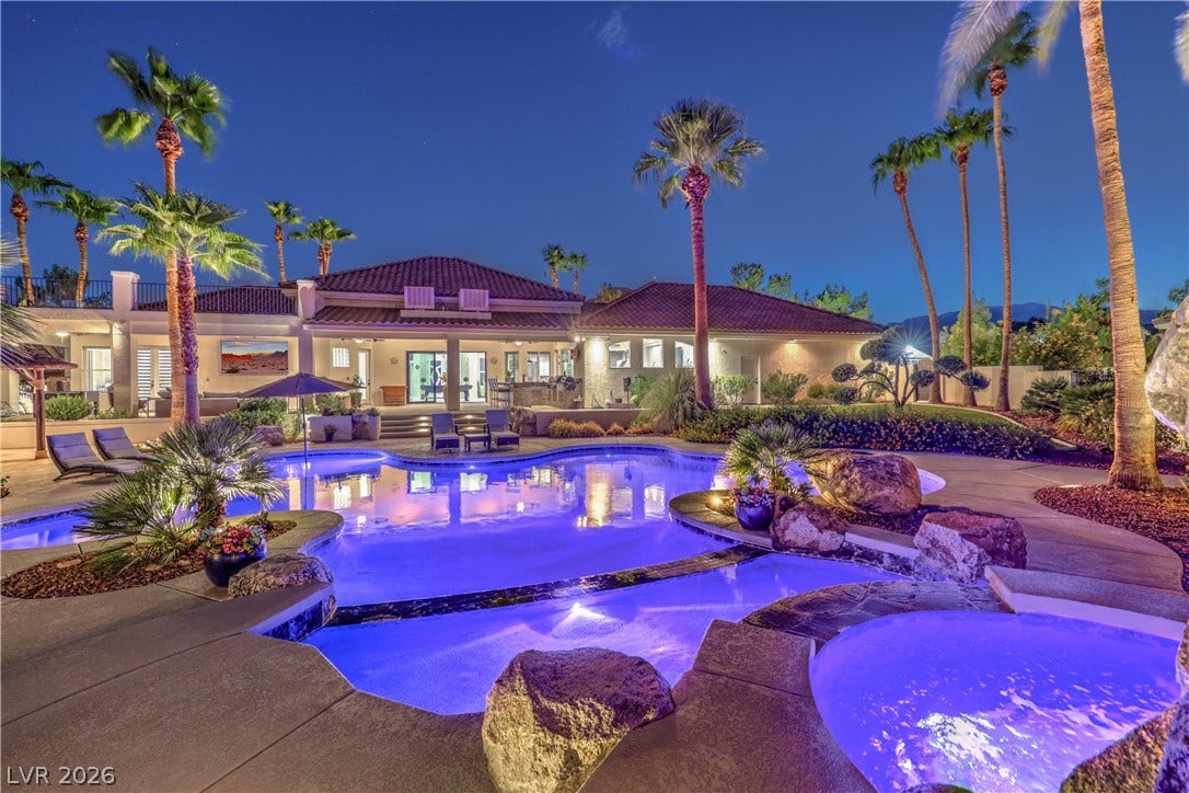 An inviting pool and integrated spa sit nestled among mature palm trees and lush landscaping.