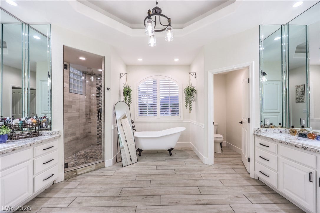 A spacious bathroom features dual vanities, a freestanding clawfoot tub, and a walk-in shower.