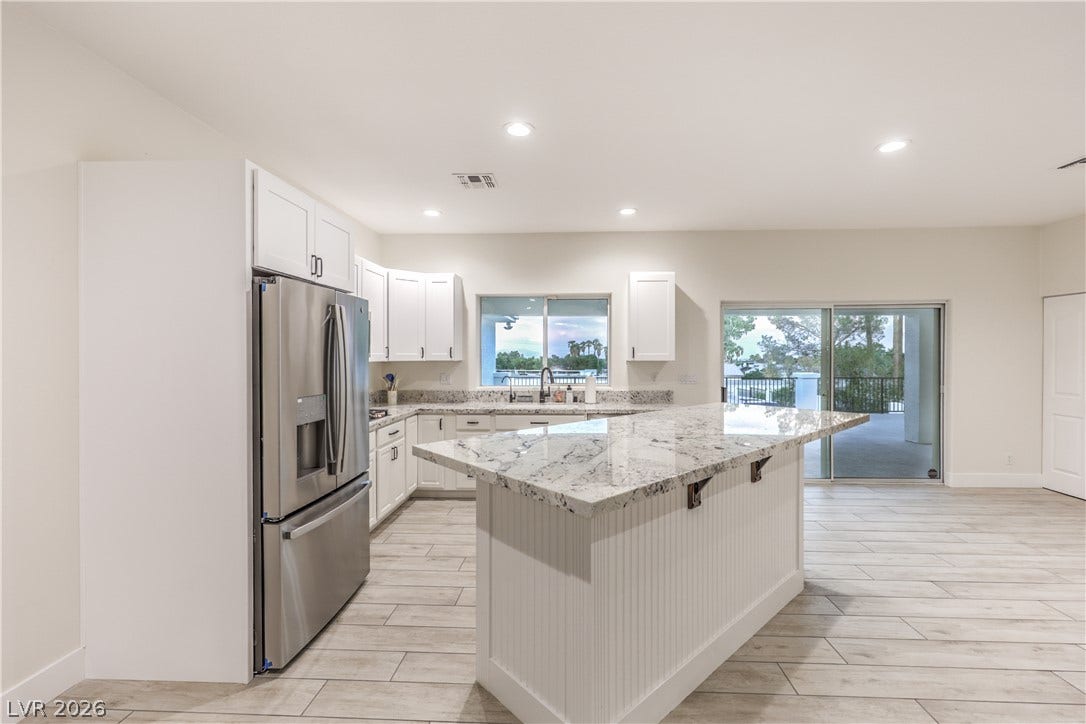 Gleaming stone countertops and a spacious central island anchor this light-filled modern culinary space.