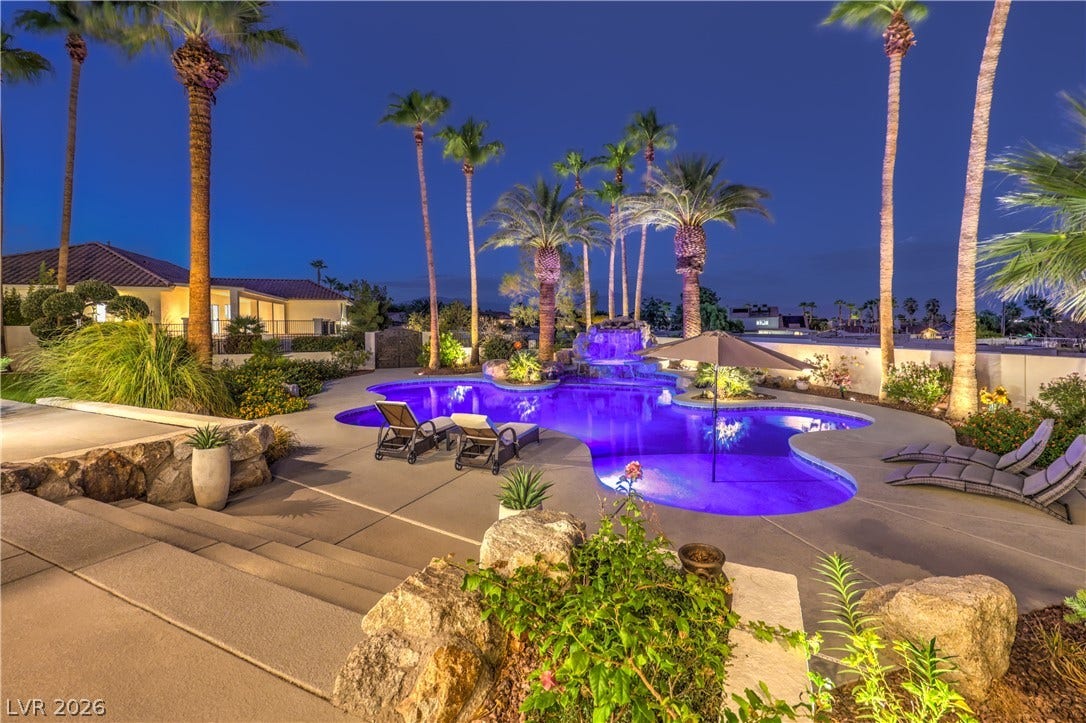 A resort-style swimming pool integrates natural stone accents under towering palm trees.