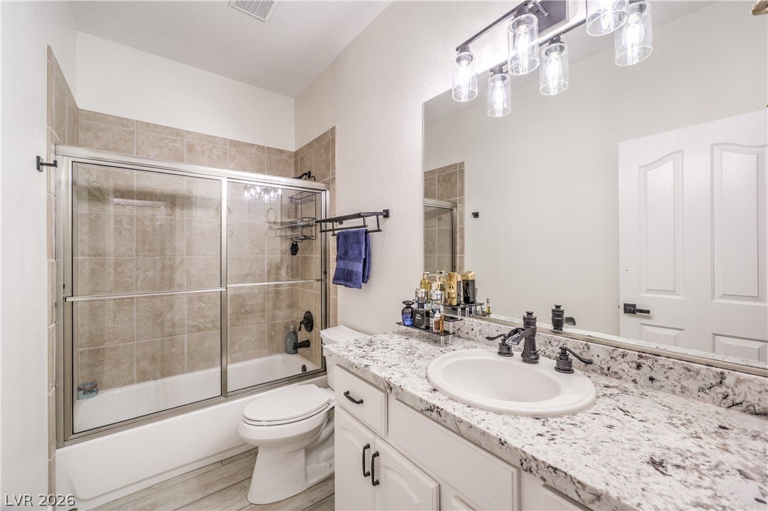 Polished stone counters and a tiled shower stall define this modern bathroom.
