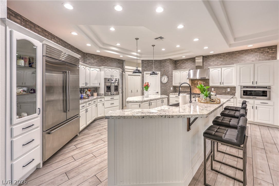 Granite countertops and rich brick accent walls define this spacious gourmet kitchen with premium appliances.