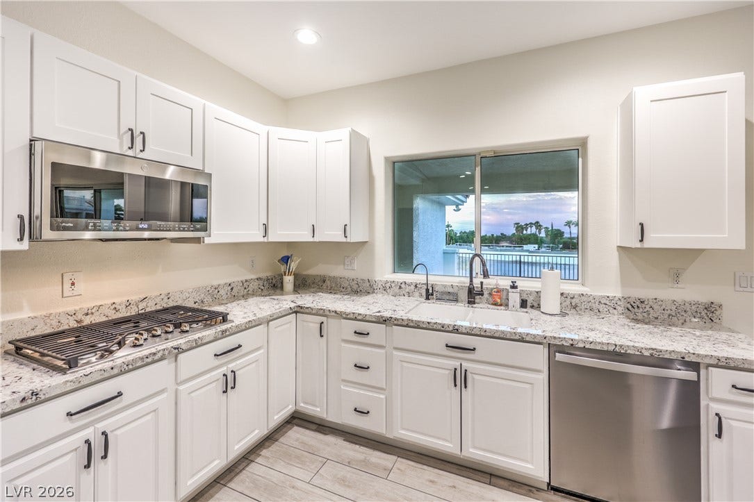 Gleaming stone countertops and modern cabinetry frame a scenic window view.