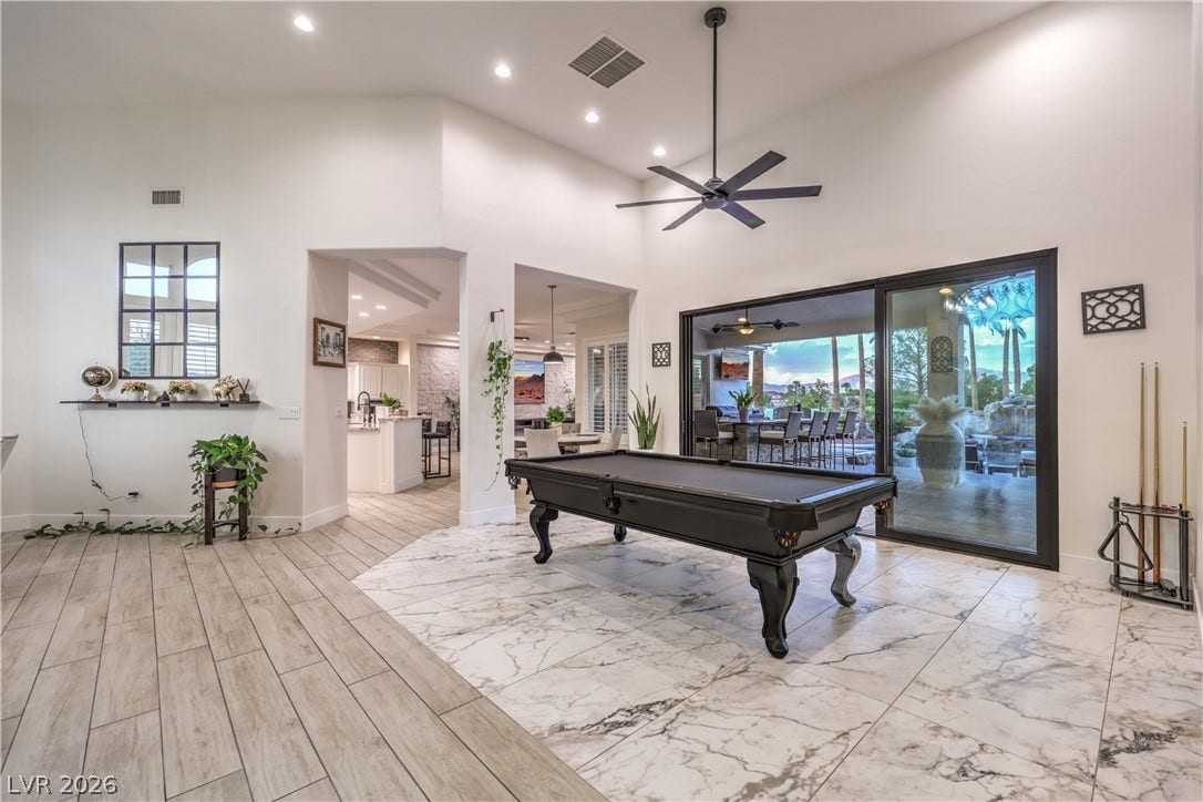 Soaring ceilings and elegant tile floors define this spacious game room opening to the outdoors.