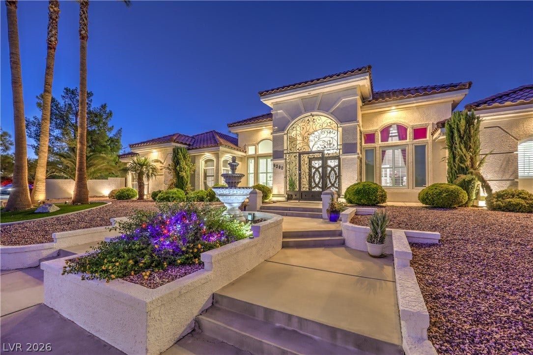An arched wrought-iron entryway and manicured landscaping create a stately first impression.