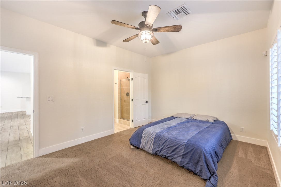 A spacious bedroom offers plush carpeting and direct access to an en-suite bathroom.