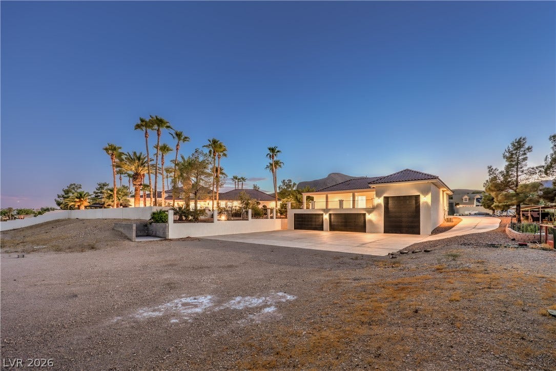 An expansive concrete driveway leads to a multi-car garage with a tile roof.