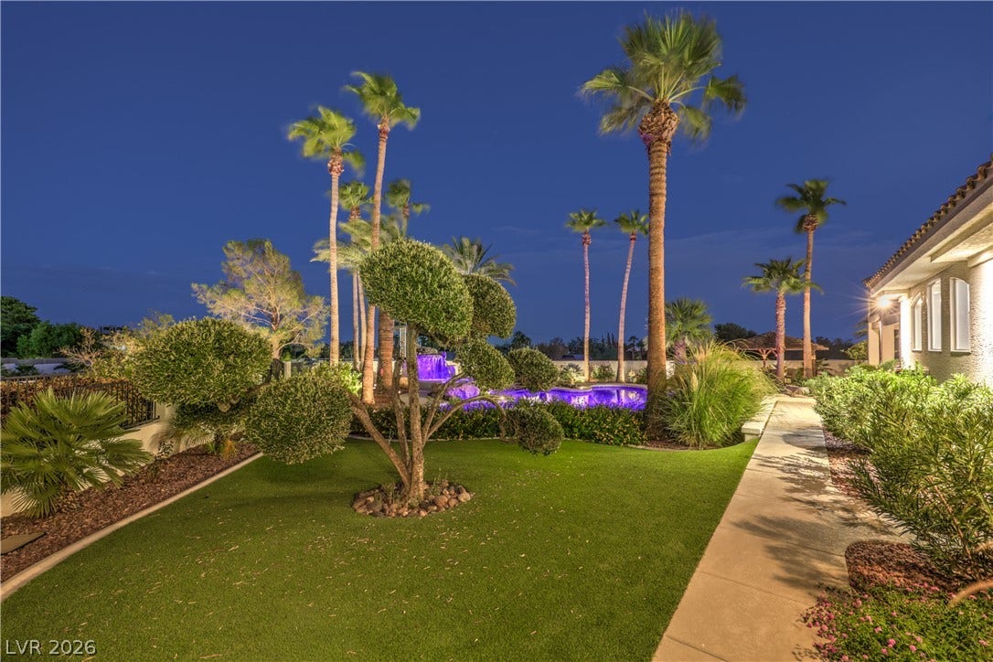 A paved path winds through manicured grounds bordered by palm trees and lush greenery.