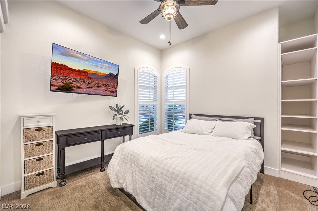 Plentiful natural light streams through arched windows fitted with elegant plantation shutters.