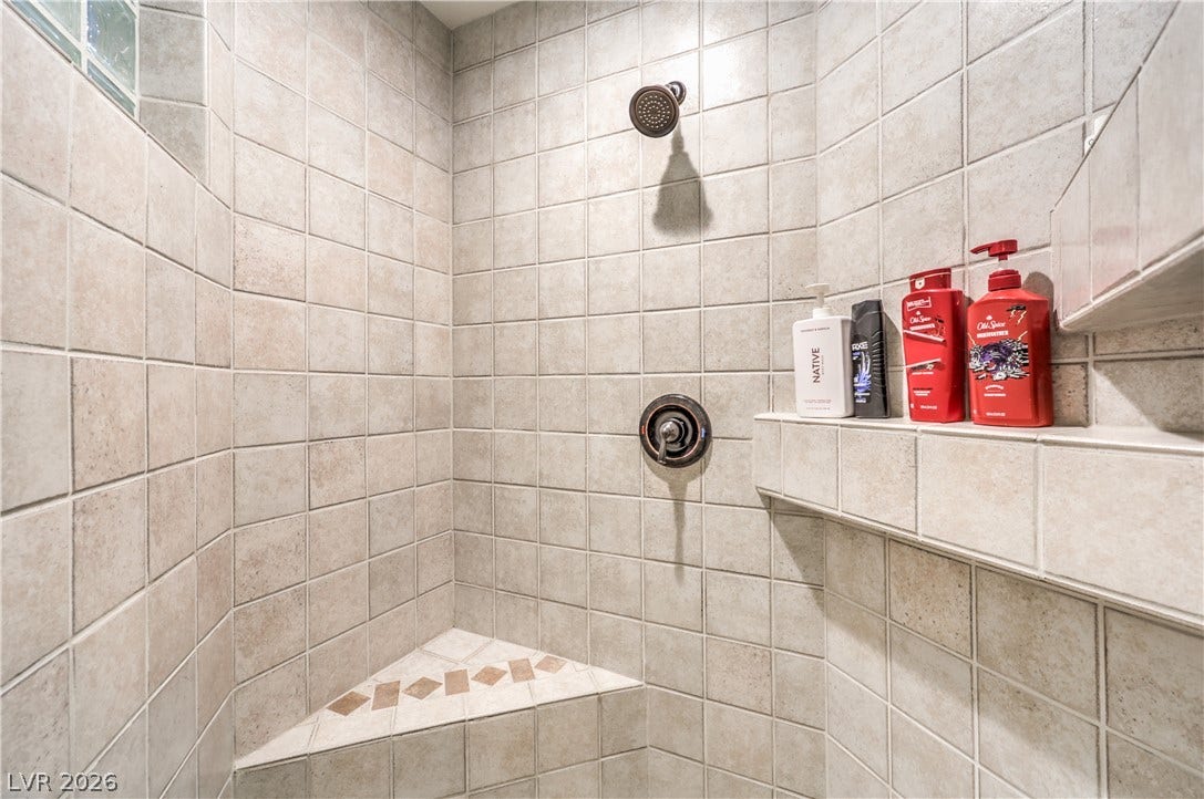 A fully tiled walk-in shower features a built-in corner bench and integrated storage ledge.