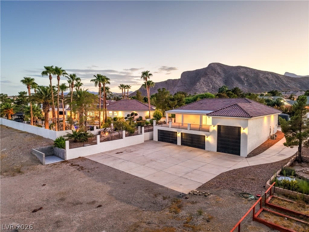 9390 Stange Avenue, Las Vegas, NV 89129 A spacious driveway and multi-car garage sit against a majestic mountain backdrop.