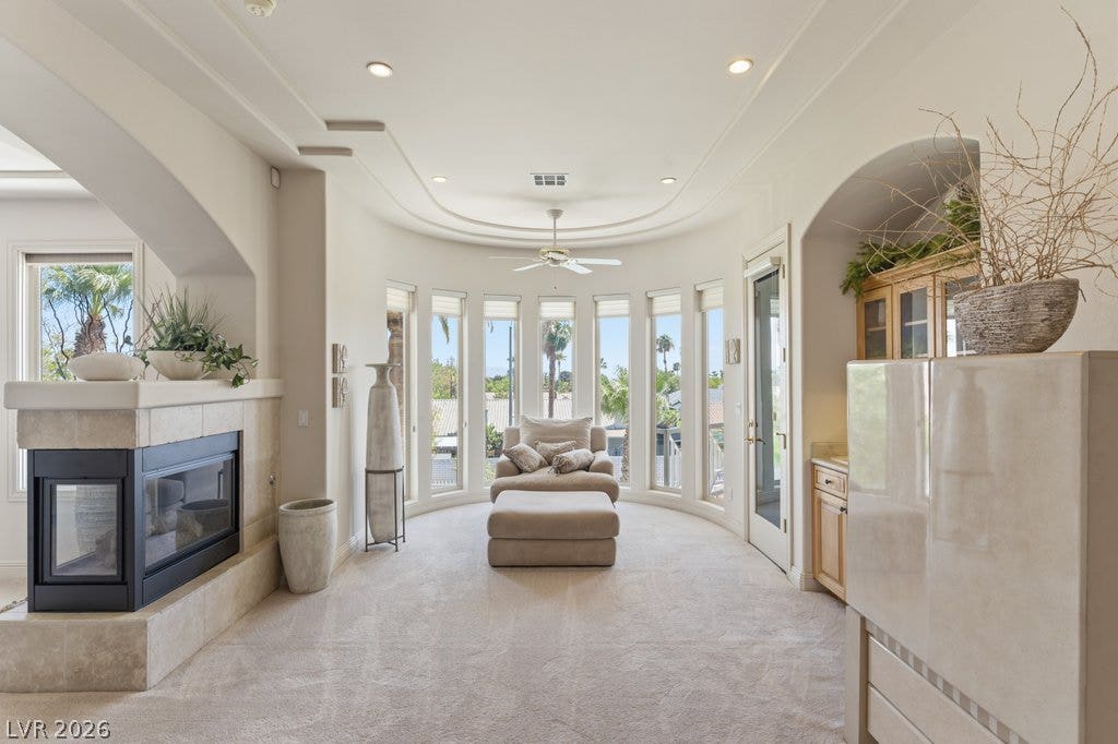 1632 Marbella Ridge Court, Las Vegas, NV 89117 An elegant fireplace warms this sun-drenched room featuring a curved wall of tall windows.