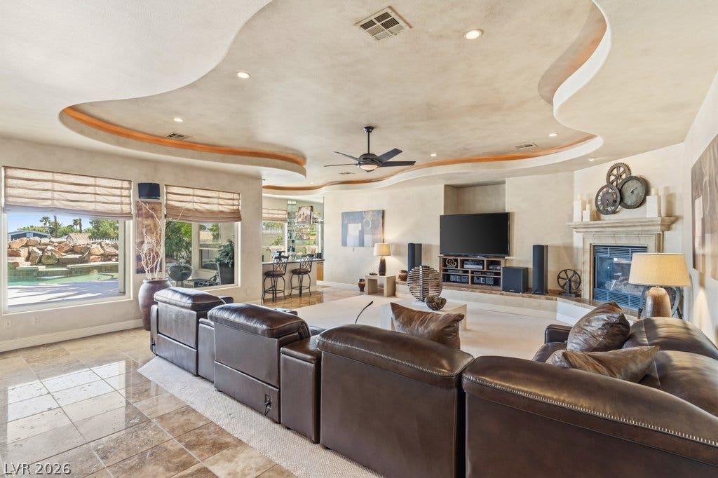 1632 Marbella Ridge Court, Las Vegas, NV 89117 A sweeping tray ceiling frames this open living space featuring a fireplace and tile flooring.