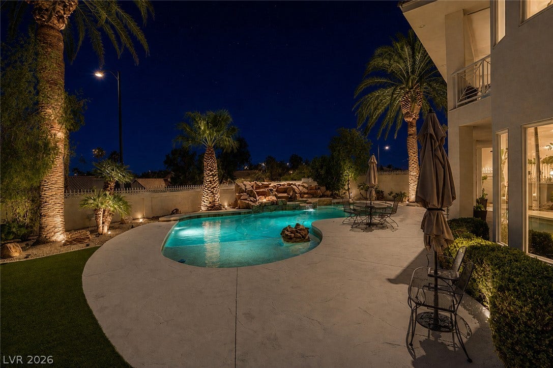1632 Marbella Ridge Court, Las Vegas, NV 89117 An inviting backyard oasis features a heated pool with water details under palm trees.