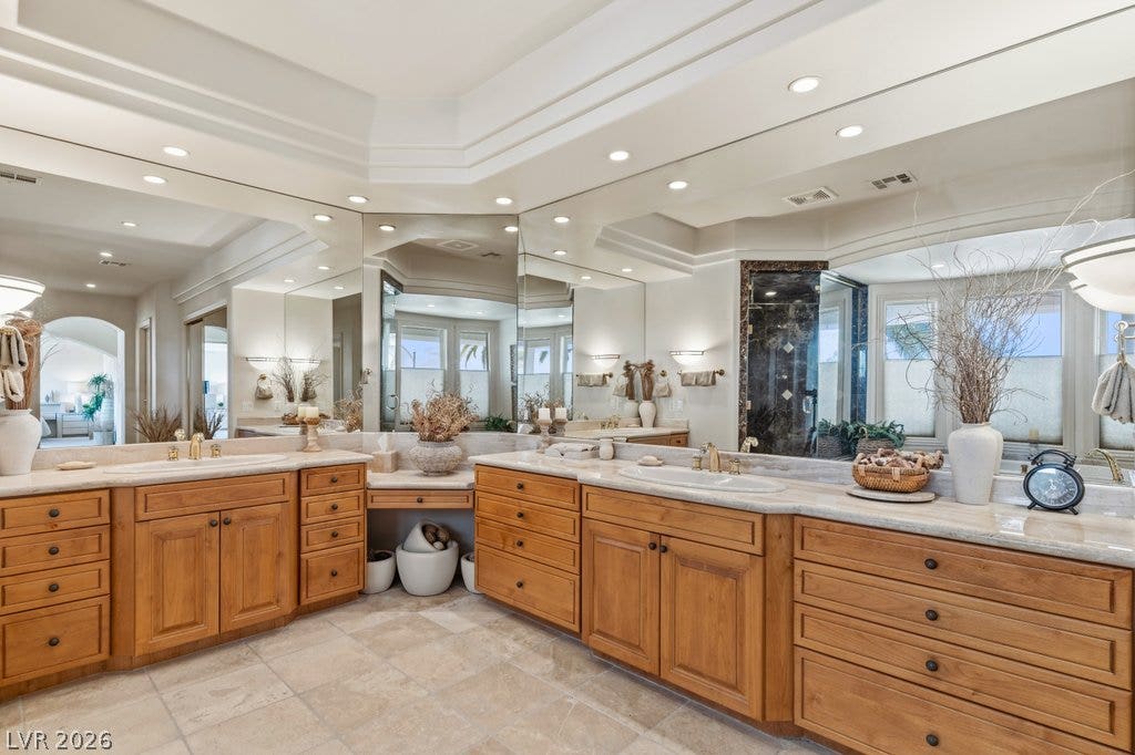 1632 Marbella Ridge Court, Las Vegas, NV 89117 Double vanities with rich wood cabinetry and stone countertops anchor this classic bathroom design.