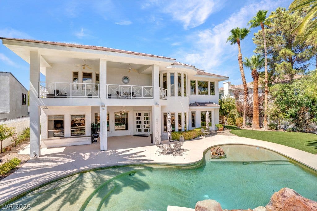 1632 Marbella Ridge Court, Las Vegas, NV 89117 An inviting backyard oasis features a curved swimming pool set against a two-story stucco exterior.