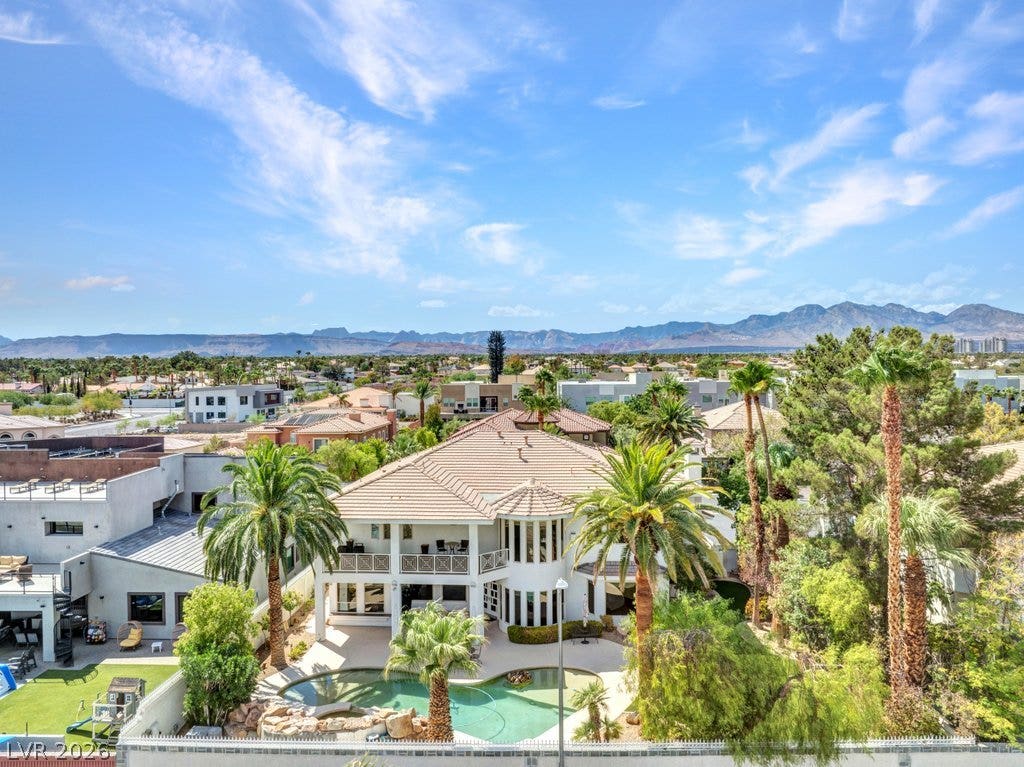 1632 Marbella Ridge Court, Las Vegas, NV 89117 A spacious backyard patio features an in-ground pool surrounded by palm trees and mountain backdrops.
