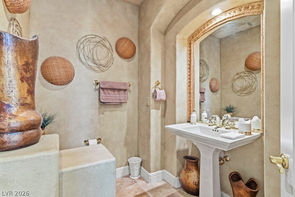 1632 Marbella Ridge Court, Las Vegas, NV 89117 Tuscan-inspired plaster walls and stone tile flooring elevate this elegant powder room.