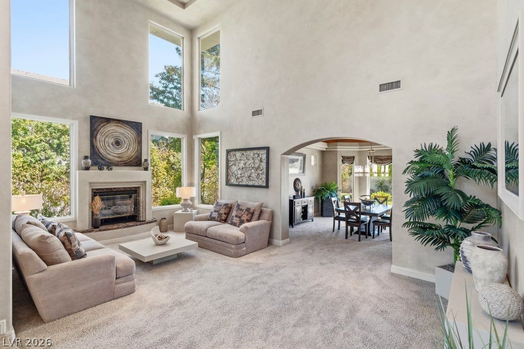 1632 Marbella Ridge Court, Las Vegas, NV 89117 Towering ceilings and multi-tiered windows frame the fireplace in this light-filled living area.